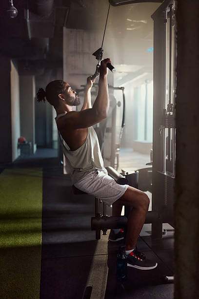 istock Black sportsman exercising on lat pull down machine in a gym. 2210184444
