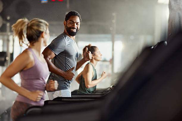 istock Happy athletic people talking while jogging on treadmills in a gym. 2210186536