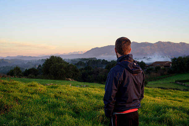 istock Man standing backside in beautiful country landscape at sunset 2210186717