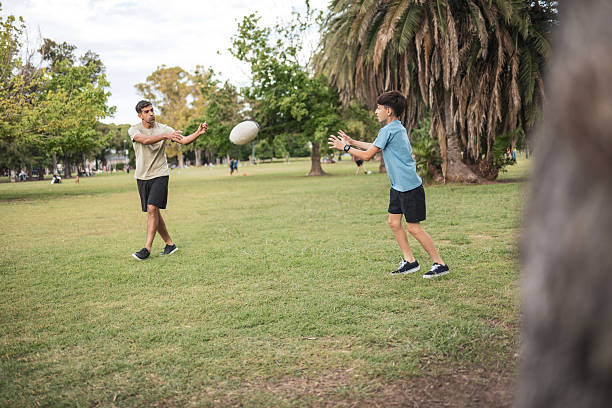 istock Father and son playing rugby together in a sunny park setting 2210188284