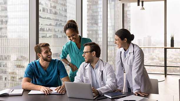 istock Happy multiethnic doctors team gather around notebook at meeting room 2210189727