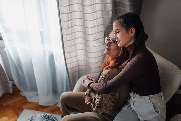 istock Teenage daughter embracing mother while looking out window 2210190777
