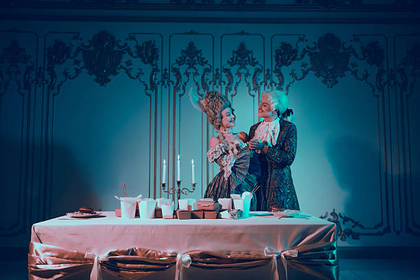 istock Elegant Couple in Aristocratic Costumes Beside Dinner Table Illuminated by Blue Light, Evoking Historical Period Drama 2210192678