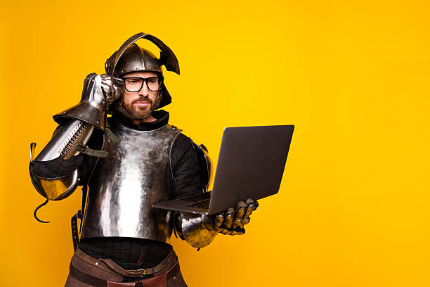 istock Medieval knight modernized with glasses and laptop on vibrant yellow backdrop 2210193113