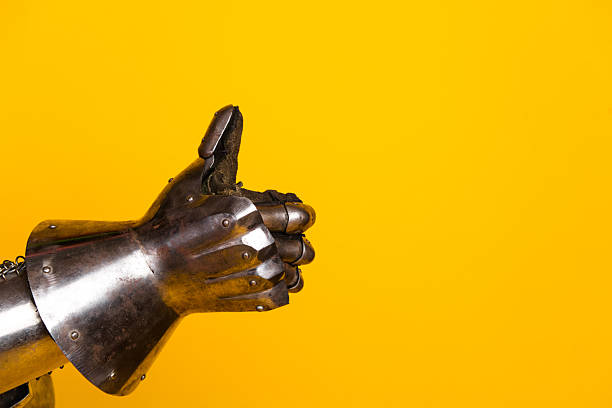 istock Iron gauntlet raised in a thumb-up gesture against a solid yellow background 2210193200