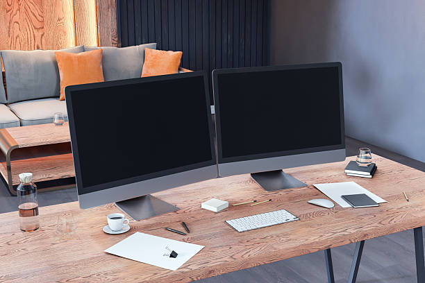 istock Modern office interior with dual computer monitors on wooden desk, minimalistic workspace setup and cozy lounge area in background. 3D Rendering 2210193502