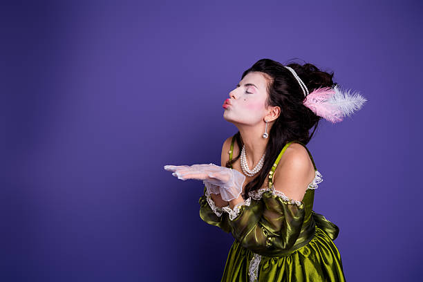 istock Woman in glamorous baroque attire posing against a deep violet background, featuring an elegant costume with green accents 2210193667