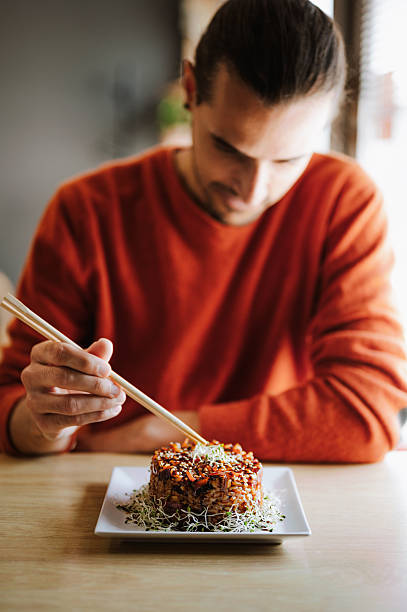 Man eating japanese rice dish with vegetables.