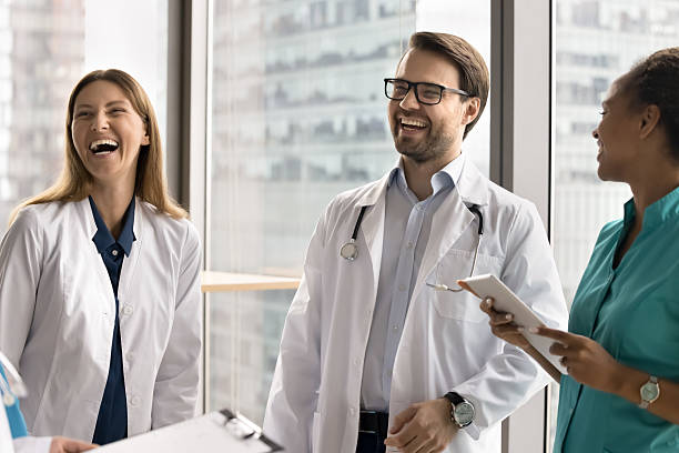 istock Cheerful laughing diverse millennial doctors group chatting by panoramic window 2210195026