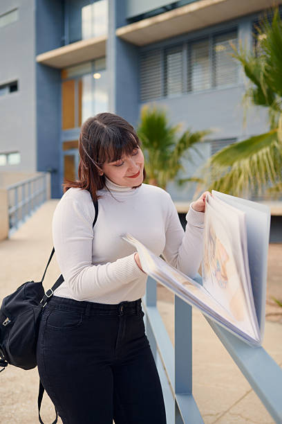 istock Art student reviewing her portfolio outdoors near university building 2210196125