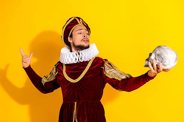 istock Man Dressed as a Nobleman Holding a Skull Against a Yellow Background for a Dramatic Comparison of Past and Modern Life 2210196895
