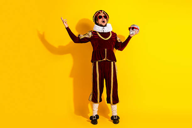 istock Young man in medieval-style costume holding a skull with sunglasses in a performance setting against a bright yellow background. 2210196941