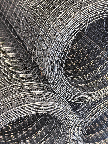 Metal wire mesh rolls stacked neatly in a warehouse setting