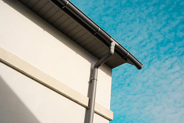 istock Building corner with downspout against a bright blue sky filled with clouds 2210197603