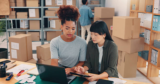 istock Collaboration, planning and technology with people in distribution warehouse for logistics or supply chain. Laptop, shipping and tablet with team in office for order delivery or boxes or packages 2210198176