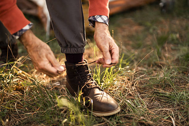 istock Person Tying Boots Outdoors in Camping Setting 2210198395
