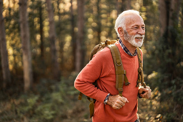 istock Elderly Man Hiking in Forest with Backpack Enjoying Nature and Fresh Air 2210198467
