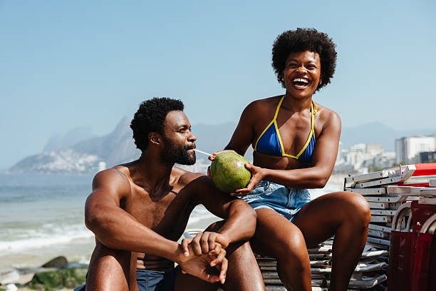 istock Playful couple enjoying beach vacation with coconut drink 2210199977