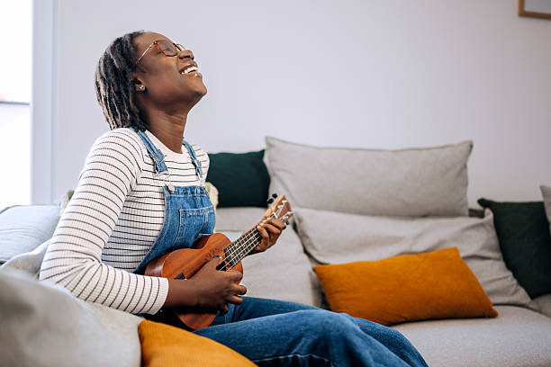 istock Young beautiful woman plays ukulele at home 2210200755