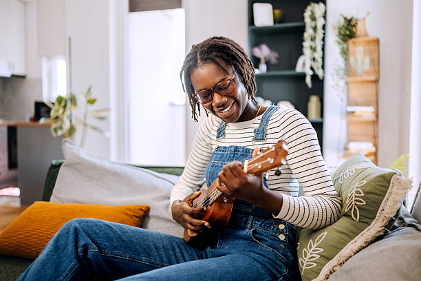 Young beautiful woman plays ukulele at home
