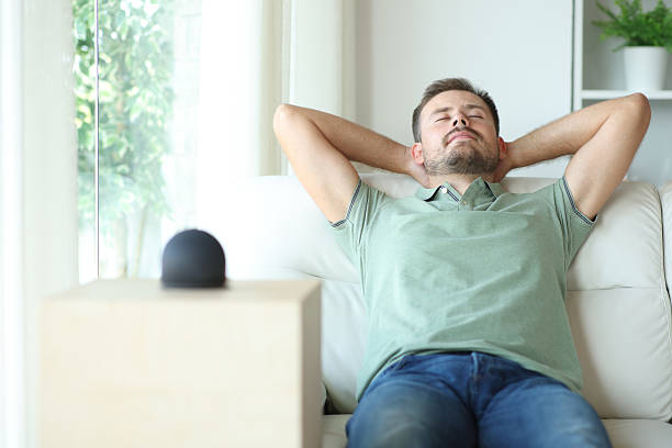 istock Man relaxing at home beside a smart speaker 2210201162