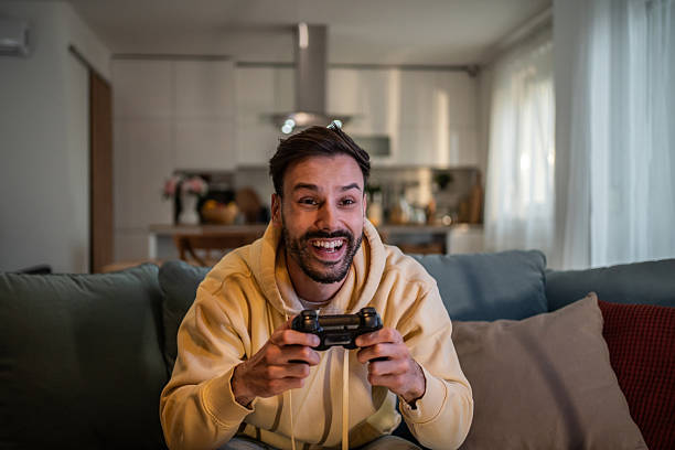 istock Excited young man playing video games at home on the couch 2210206380