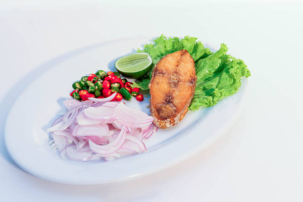 Salted fish, Crispy Mackerel with Fish Sauce, Crispy mackerel fillet fried with fish sauce, served with sliced red onion, chopped chili, fresh lime, and green lettuce