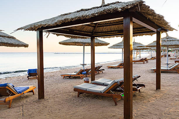 istock Relaxing beachside cabanas provide shade at sunset on a serene shoreline with lounge chairs 2210207799