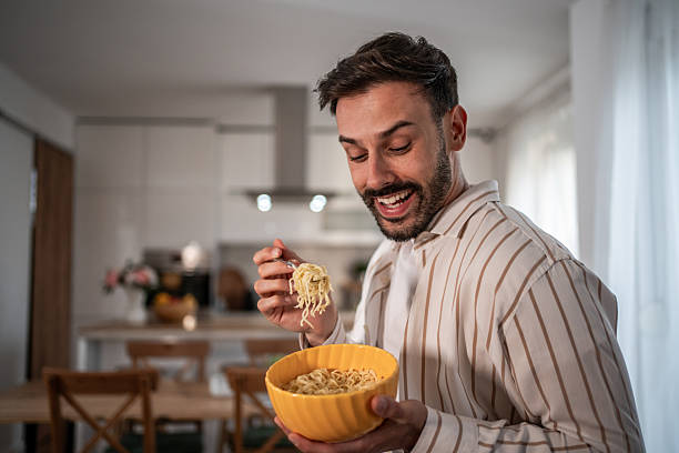 istock Happy man eating noodles in the kitchen 2210209091