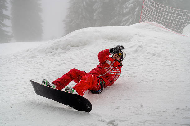 istock Snowboarder wearing red gear falling on a snow-covered slope 2210212458