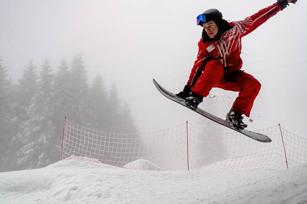 istock Snowboarder performing high jump in snowy forested mountain area 2210213269