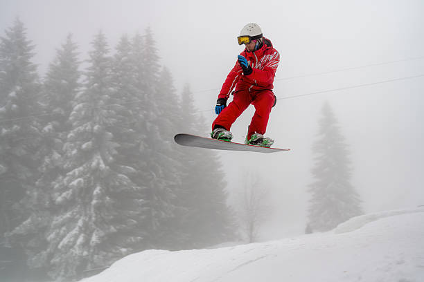 istock Snowboarder performing a jump amid snowy trees and misty background 2210213607