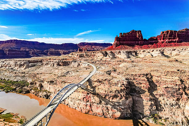 Powerful bridge - masterpiece of engineering thought among the picturesque red-brown sandstone. Hite Crossing Bridge is an arch bridge across the Colorado River. Shot from a bird's eye view