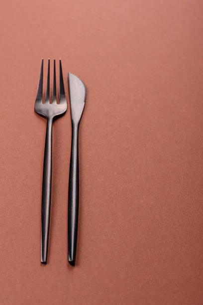 istock Knife and fork, cutlery on a brown dining table 2210217309