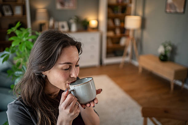 istock Young woman relaxing on sofa drinking tea at home 2210225589