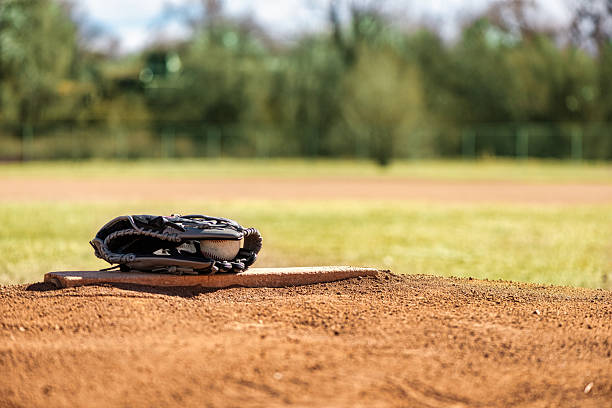 Baseball glove mitt with ball on pitchers mound and outfield in background