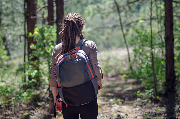 istock A young woman hikes through a lush green forest, sunlight streaming through the tree branches above. With her long natural dreadlocks and a backpack on her shoulders, she takes in the energizing tranquility of the surrounding nature. 2210231028
