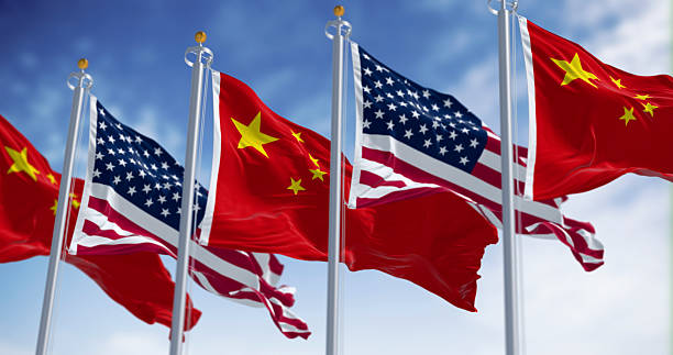istock Chinese and American flags waving together against blue sky. 3D render 2210231058