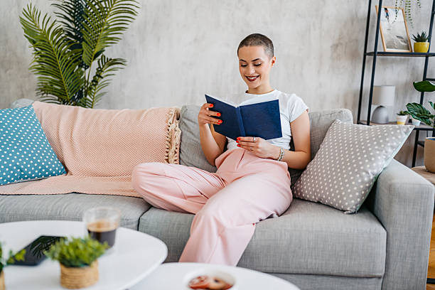 istock Young Woman With A Buzz Cut Reading A Book At Home 2210232415