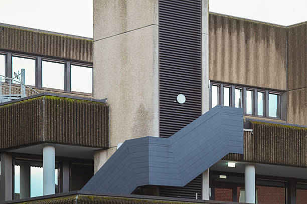 Grey concrete facade of a brutalist style building with a large outdoor staircase, showcasing the architectural textures and geometric shapes