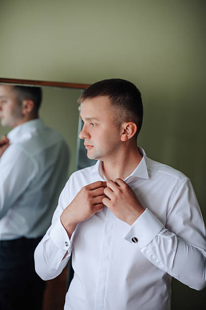 istock A man is getting dressed in front of a mirror 2210236598