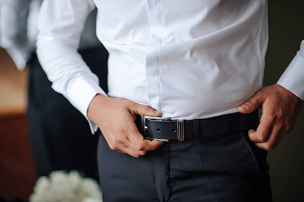 istock A man in a white shirt and black belt is adjusting his pants 2210236608
