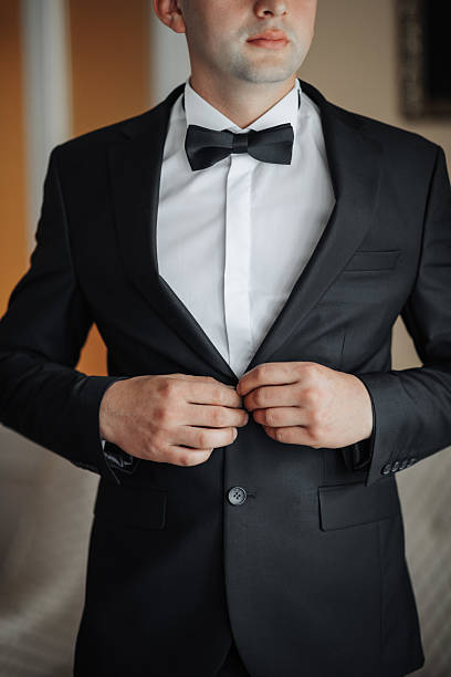 istock A man in a black suit and white shirt is getting ready to tie his bow tie 2210236633