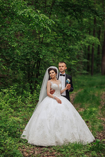 istock A bride and groom are posing for a picture in a forest 2210236785