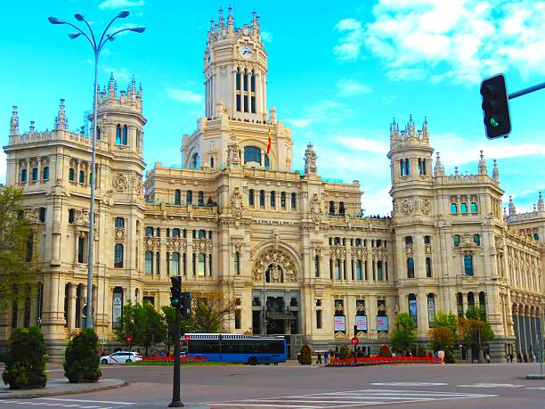 Madrid, Spain -04/13/2025   Buildings at the center of capital city. Cybele Palace (Palacio de Cibeles), the grand city hall of Madrid with a Spanish flag blowing in the wind. Cibeles Palace ( Palacio de Cibeles), formally known as Palacio de Comunicaciones (Palace of Communications) and Palacio de Telecomunicaciones (Palace of Telecommunications) until 2011,  it is now occupied by City Council of Madrid, serving as the city hall, and the public cultural centre CentroCentro.