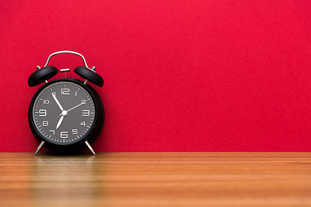 Black alarm clock on the wooden table.