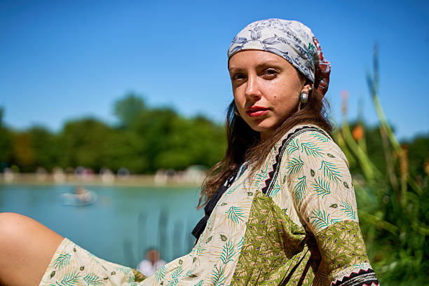 Portrait of a young woman wearing a headscarf, enjoying a sunny day by the lake in a park