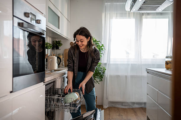 istock Young woman emptying dishwasher in modern kitchen 2210252361