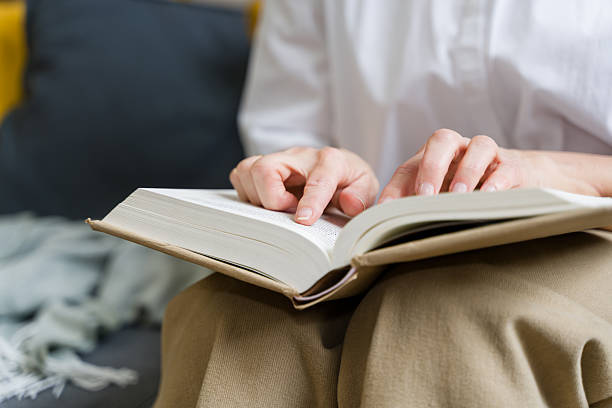 istock Woman reading a book and pointing at the text with her finger 2210252454