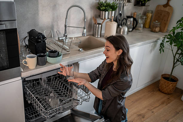 istock Young woman loading the dishwasher in a modern kitchen 2210252496